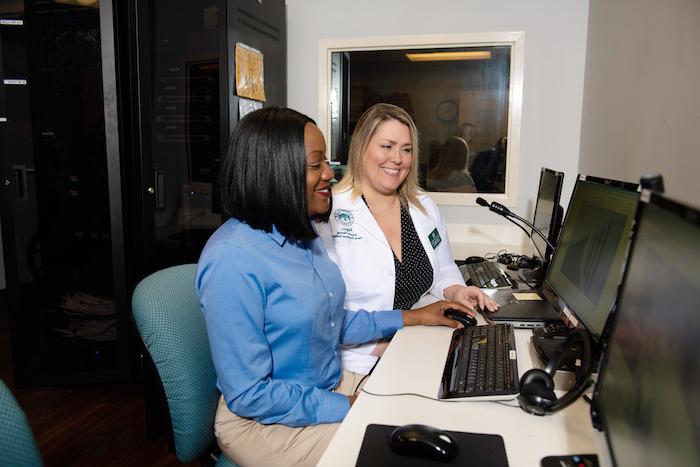 Two female healthcare professionals conferring about information on a computer.