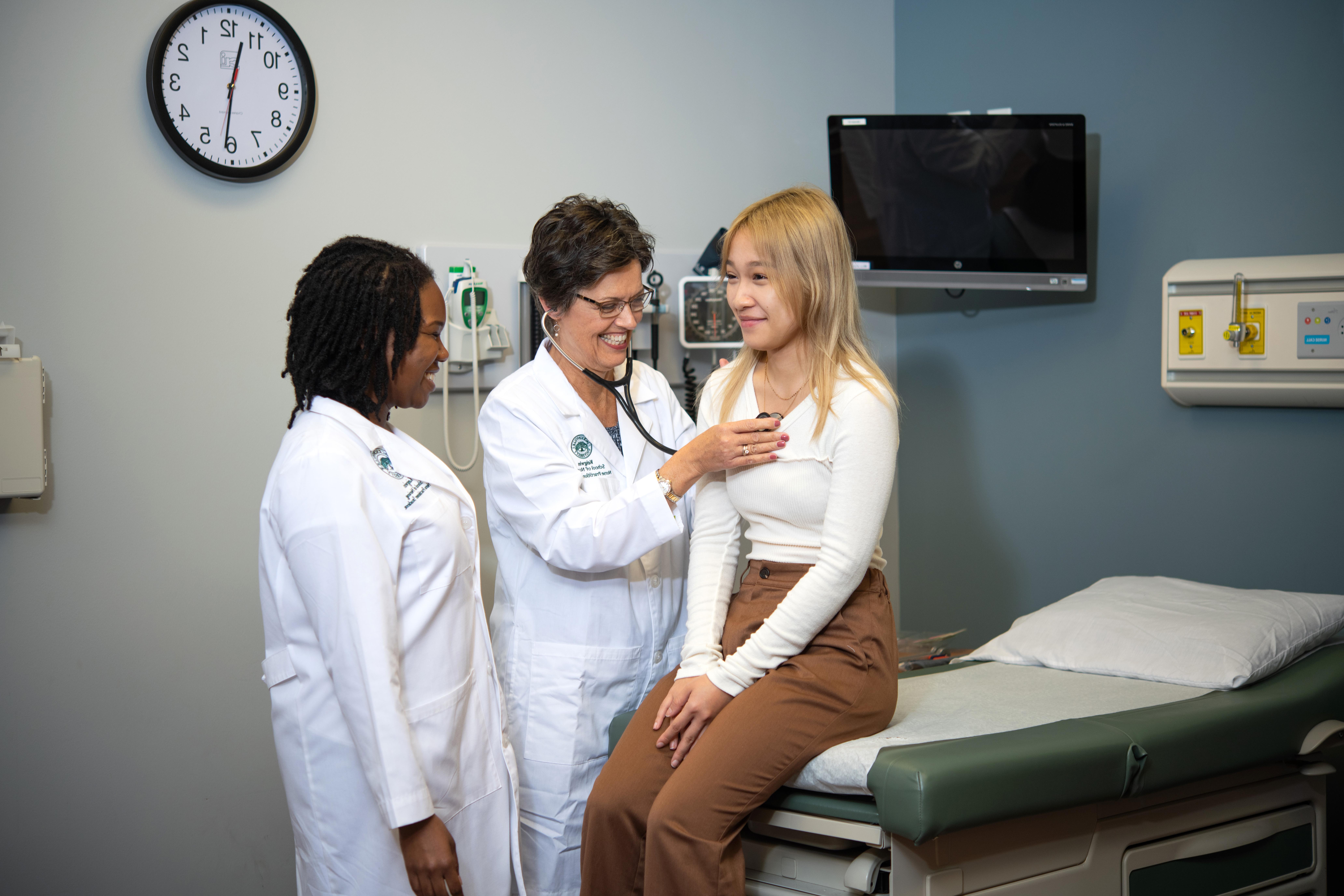 两名护士在检查室听一名女病人的心率