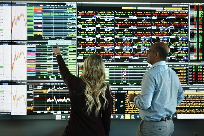 people pointing at a wall of green and red data points