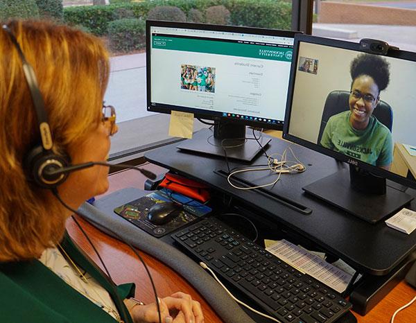 An advisor works with a student using a video chat over the computer.